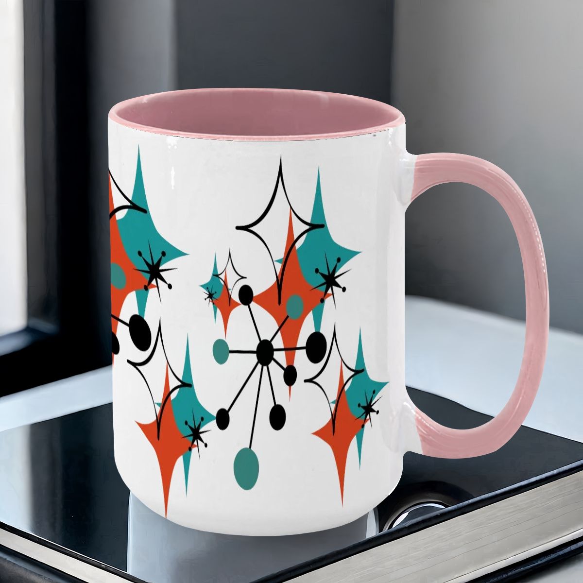 Colorful 15oz mug featuring a Mid Century Modern atomic starburst design in teal, orange, and black with a pink handle.