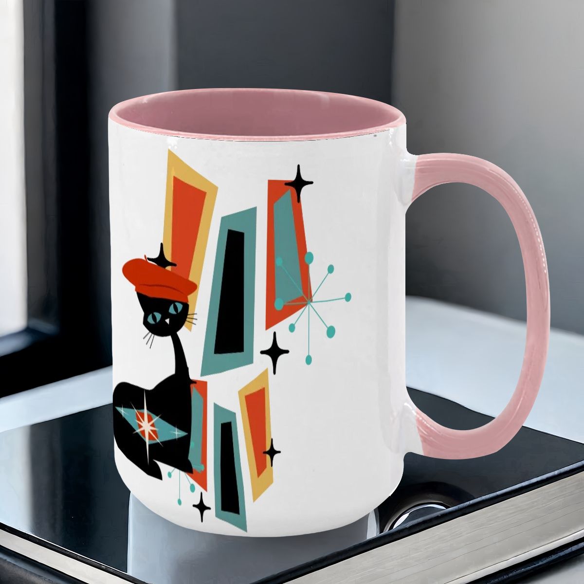 Mid Century Modern coffee mug featuring an atomic cat design with geometric shapes in teal, orange, and black.