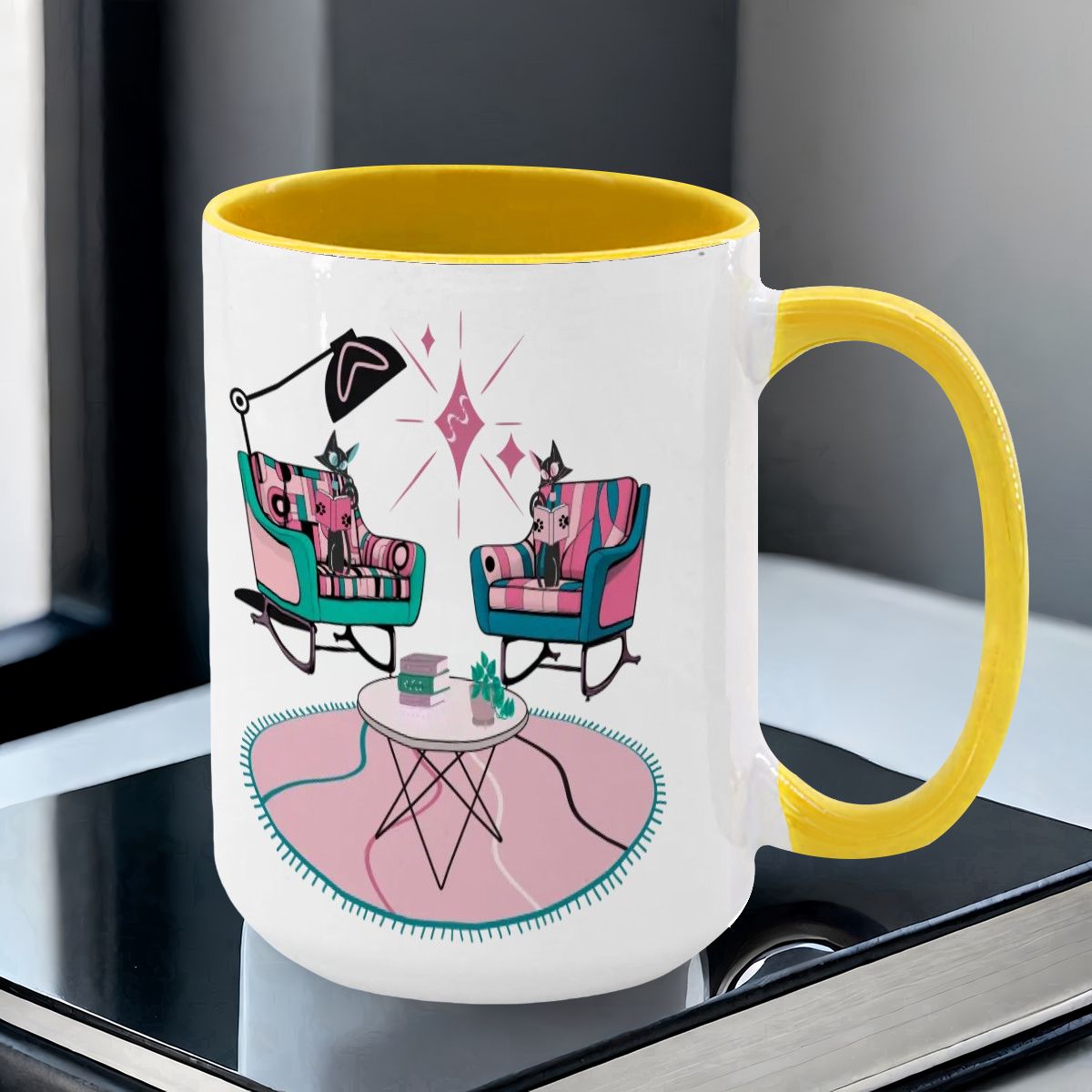 Large colorful mug featuring atomic reading cats in mid-century modern chairs, with a bright yellow handle and rim.
