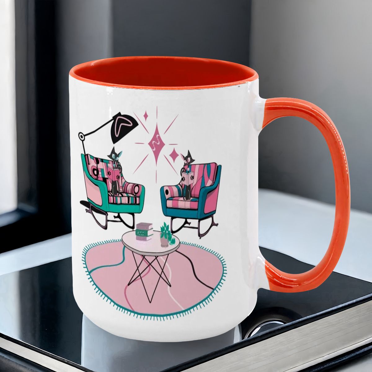 Large colorful mug featuring atomic reading cats in mid-century modern chairs, with a vibrant orange handle and interior.